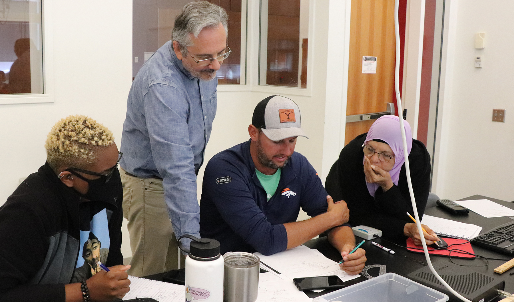 Dr. Dan Claes (second from left) discusses a PHYS 892 assignnment with Noyce teachers in the course. (Lindsay Augustyn, CSMCE)