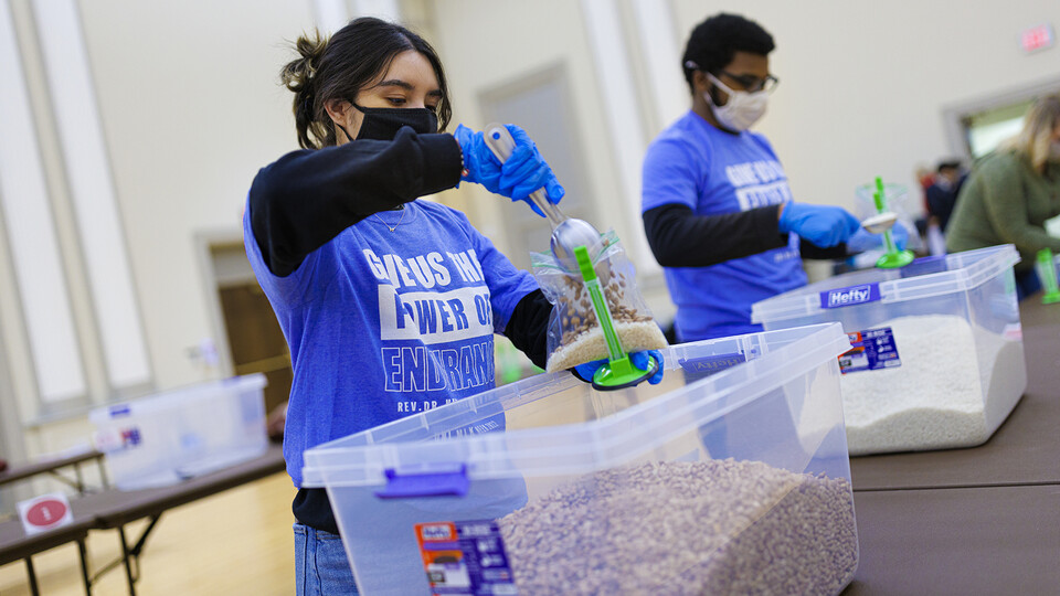 Cynthia Serrano-Ortega (left) and Christian Parrish add beans to meals being packed as part of the university’s MLK Week service project last year. 
