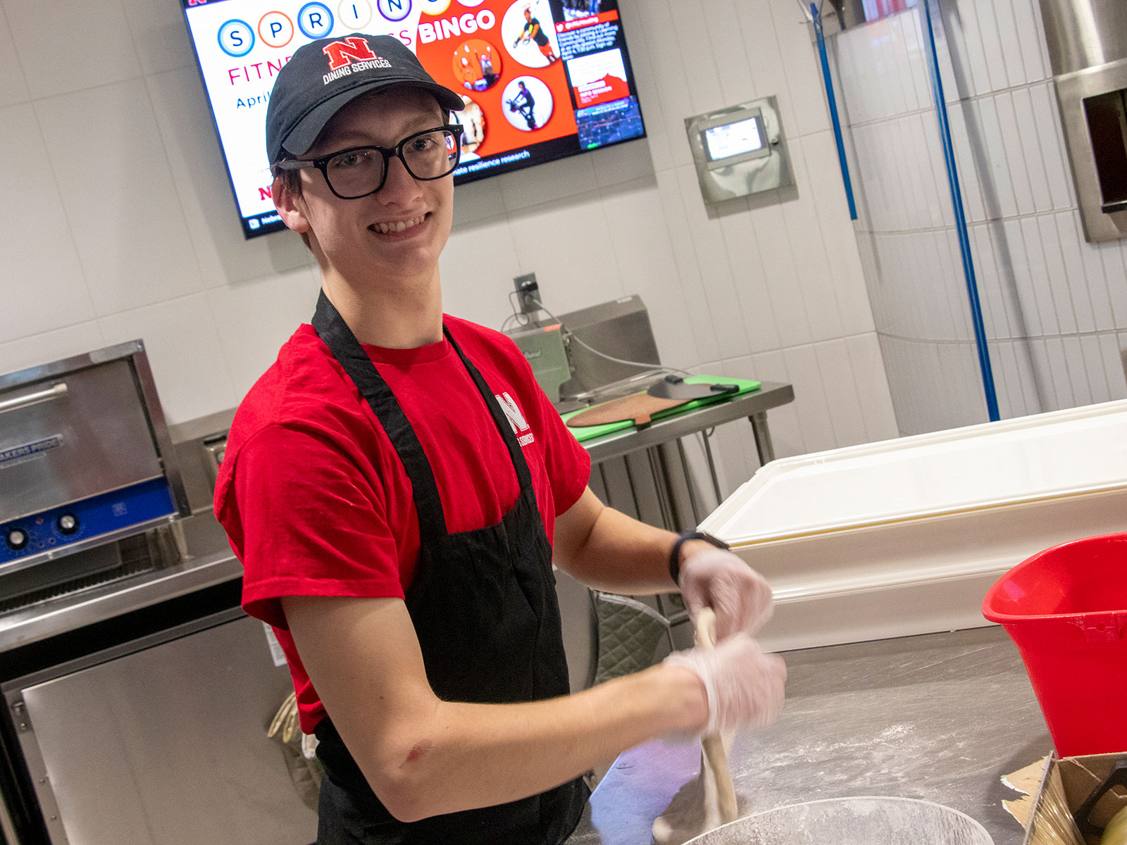 Leo Ray prepares a pizza as a dining student worker.
