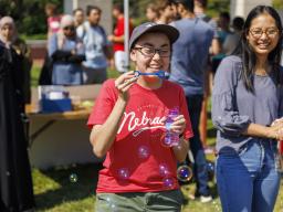 Sarah Roscoe blows bubbles at the UNL Christian Graduate Student table during the Club Fair. August 24, 2022. [Mike Jackson | Student Affairs]