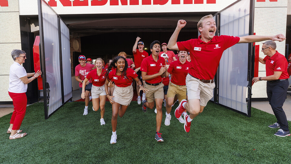 NSE orientation leader Jackson Anderson and other NSE members lead students onto the field to form the "N" for the class photo in Memorial Stadium.