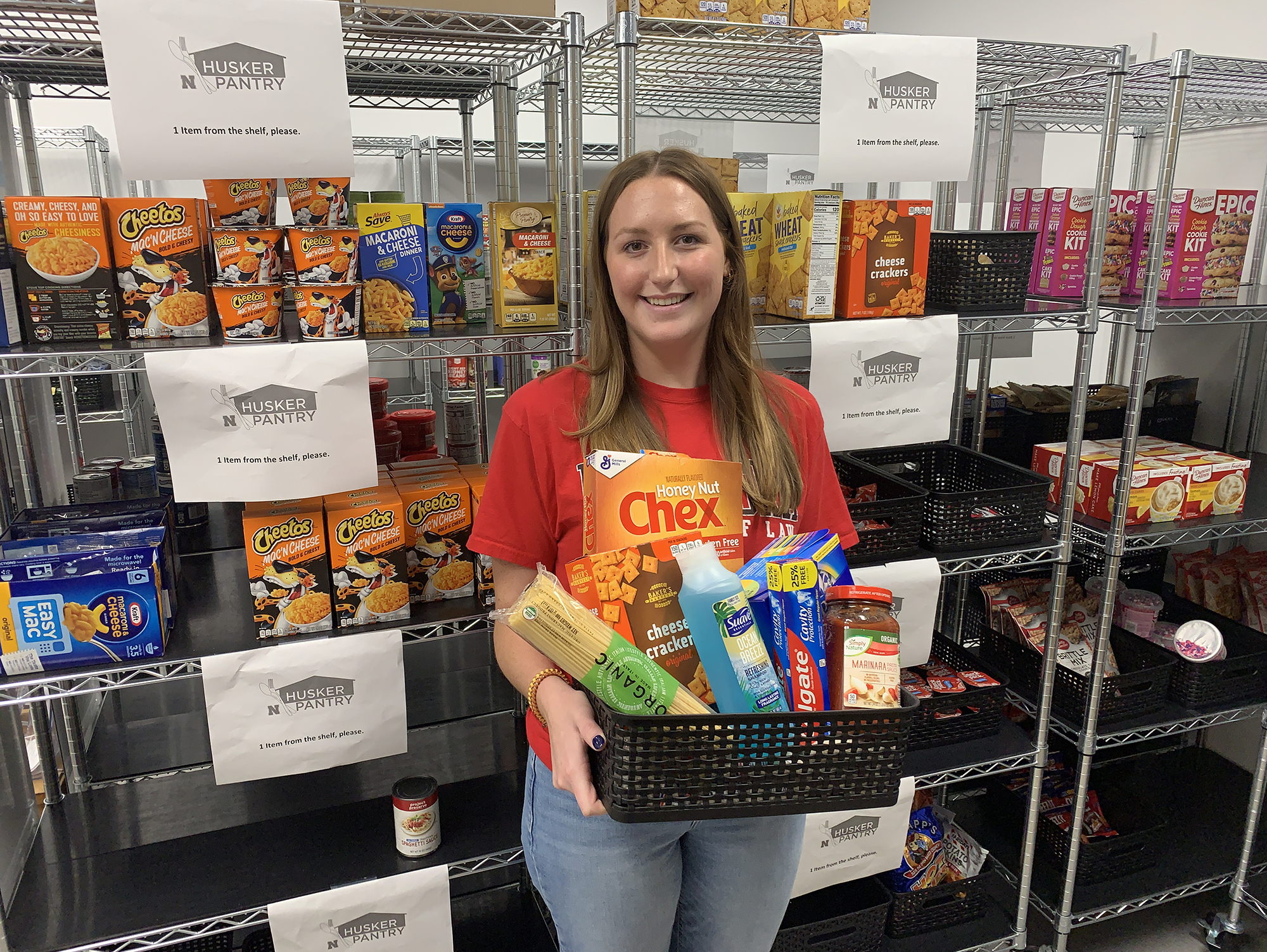 Husker Pantry graduate assistant Emilee Smith displays a basket of personal care and food items that are commonly-requested by University of Nebraska–Lincoln students. [Christopher Dulak | Student Affairs]