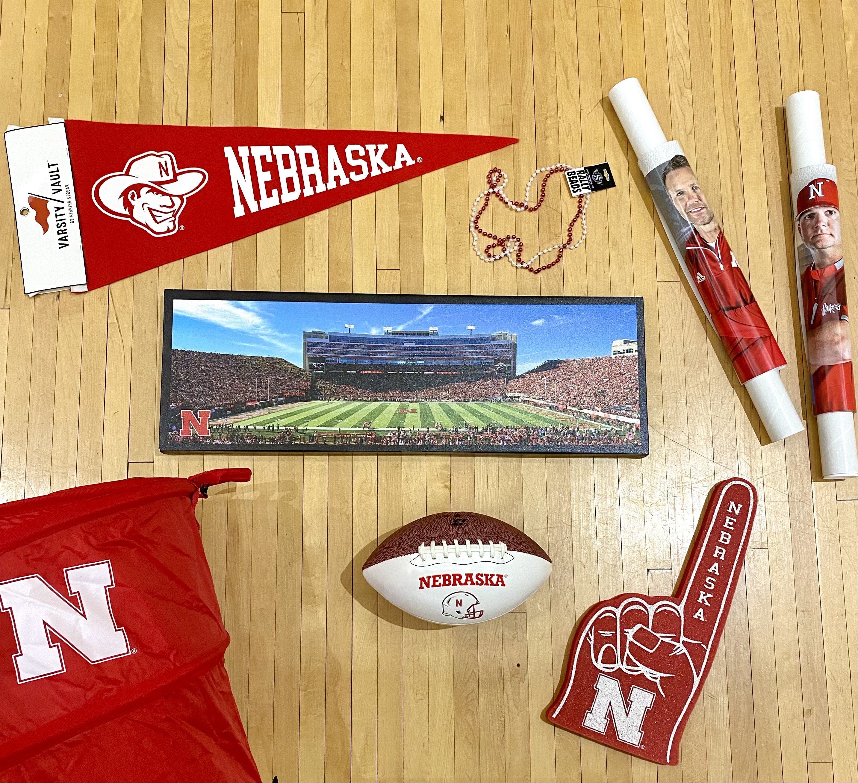 Prize pack includes Nebraska pennant flag; rally beads, posters; canvas image of Memorial Stadium; tailgate cooler; football; and a foam finger. 
