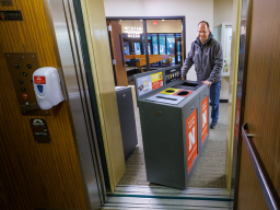 Chad Ebke, a senior material service worker with Facilities Management and Planning-Business Operations, moves a new recycling station onto the elevator in an East Campus building. [Craig Chandler | University Communication]