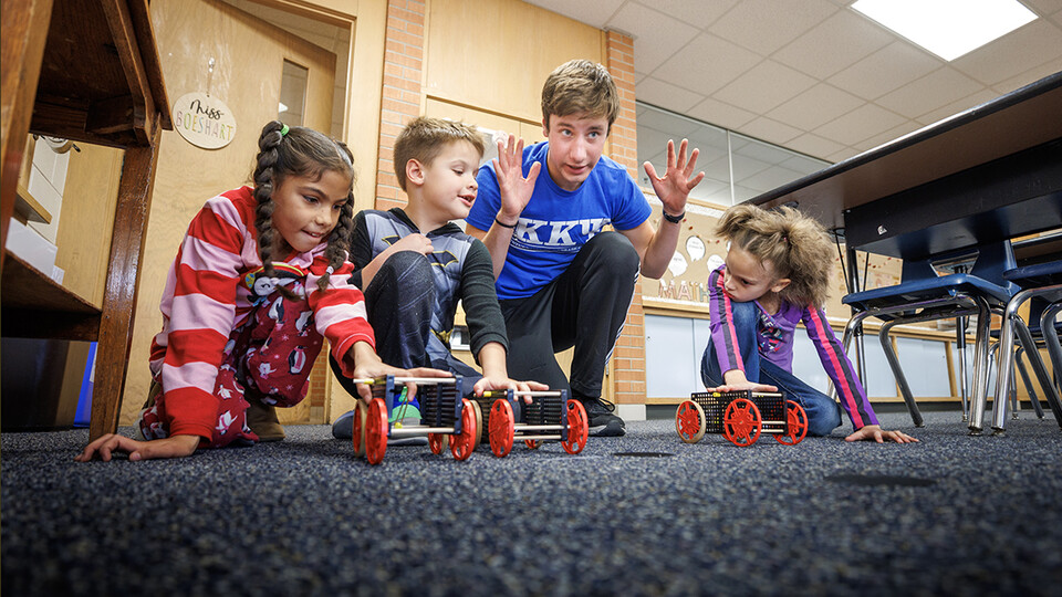 Spencer Knight gets three students and their rubber-band powered cars lined up for a race at Riley Elementary School in Lincoln. [Craig Chandler | University Communication]
