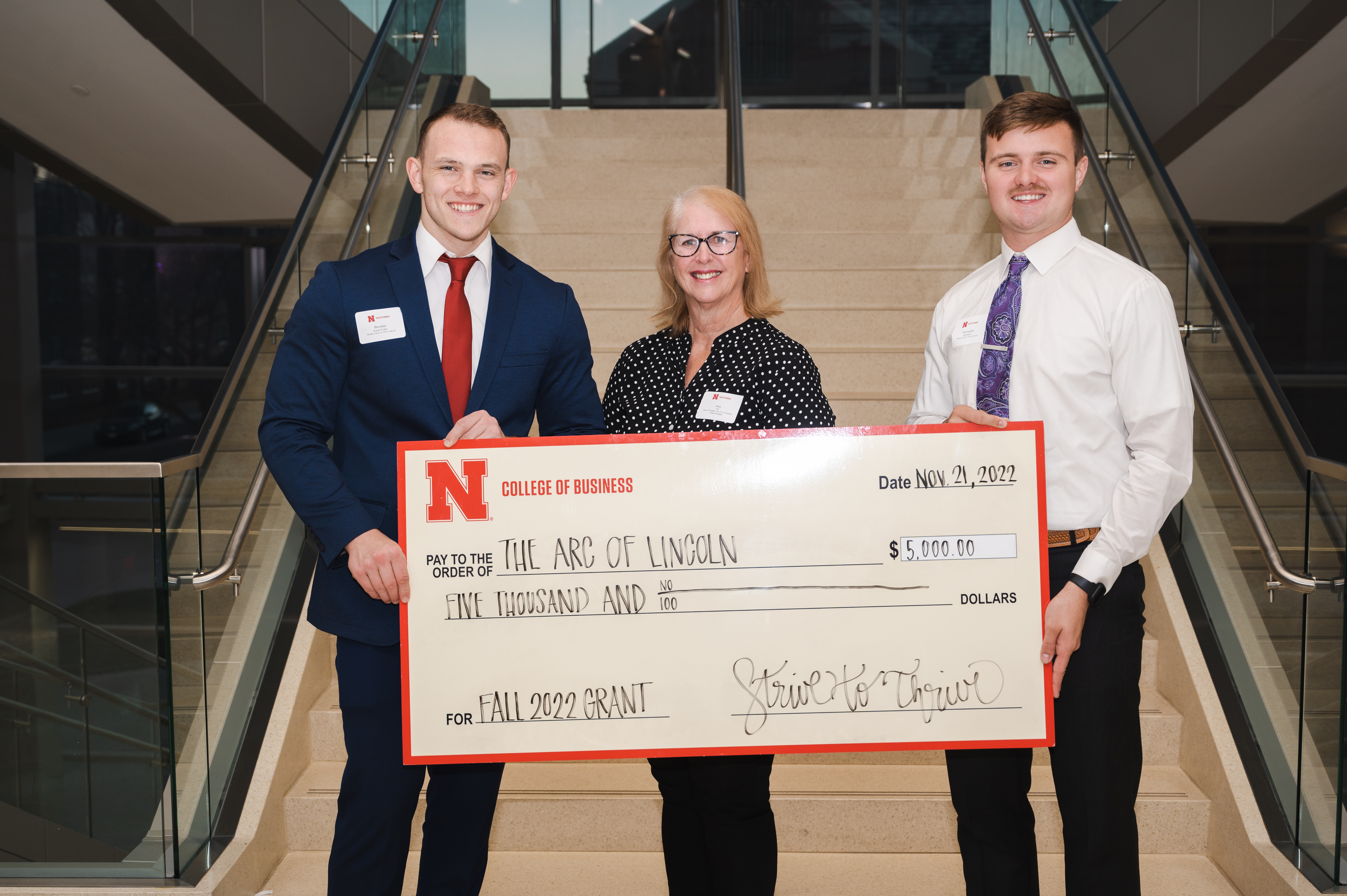 Class members Brendan Kauth-Fisher (left) and Chris Karmazin (right) present Mary Ells (center), The Arc of Lincoln Treasurer, with a Strive to Thrive Lincoln grant. Kauth-Fisher and Karmazin selected The Arc to research and for the class to consider.