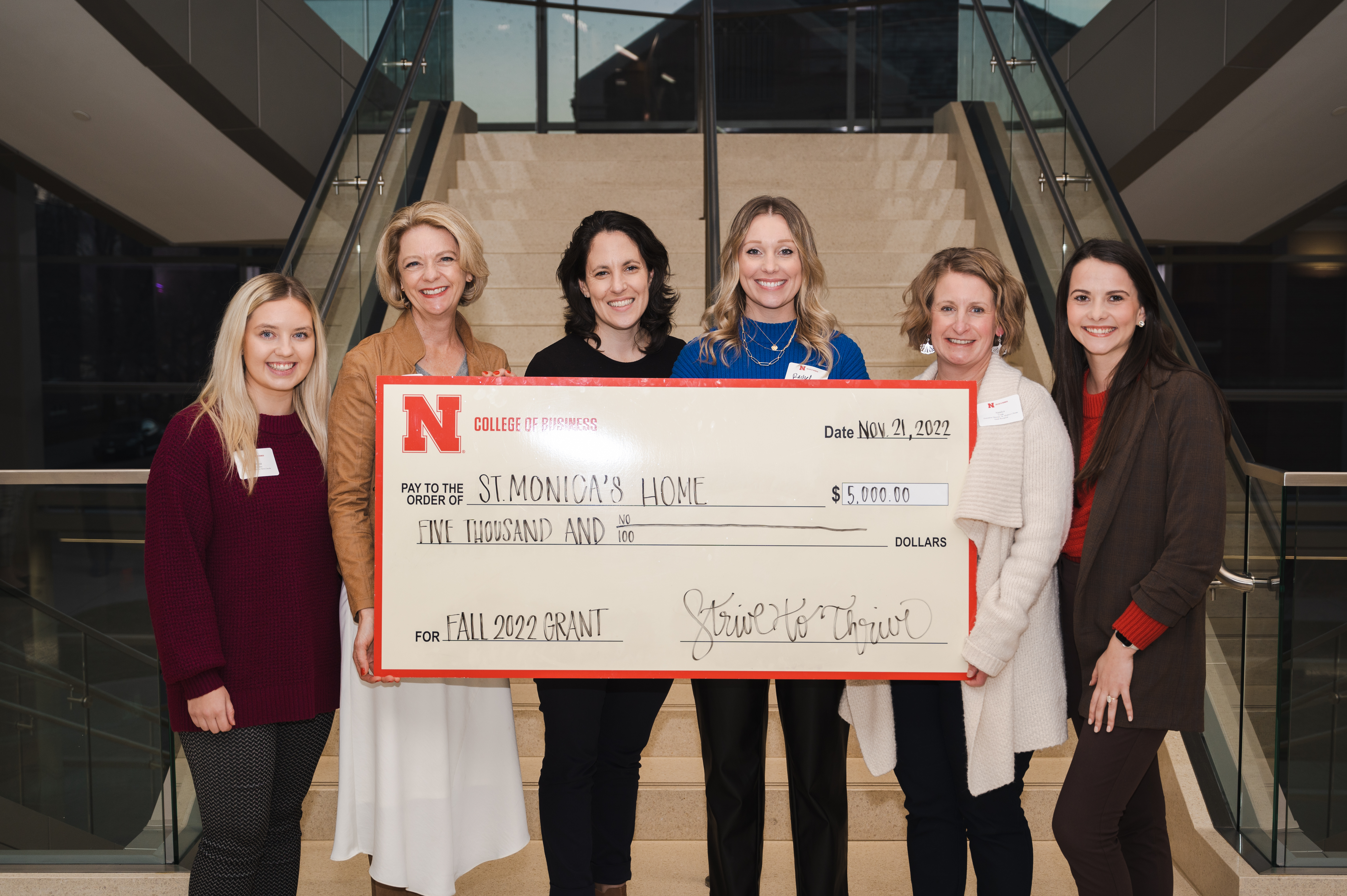 Class members Alyssa Zabawa (far left) and Grace Kanel (far right), present members of St. Monica's staff with a Strive to Thrive Lincoln grant. Zabawa and Kanel selected St. Monica's to research and for the class to consider.