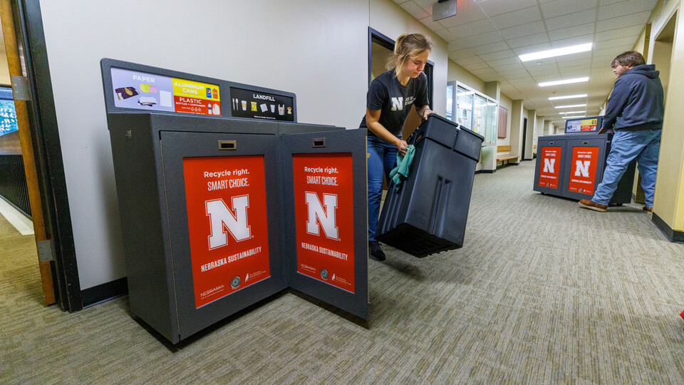 Sustainability Program Assistant Anna Oetting wipes down the new recycling stations in an East Campus building.