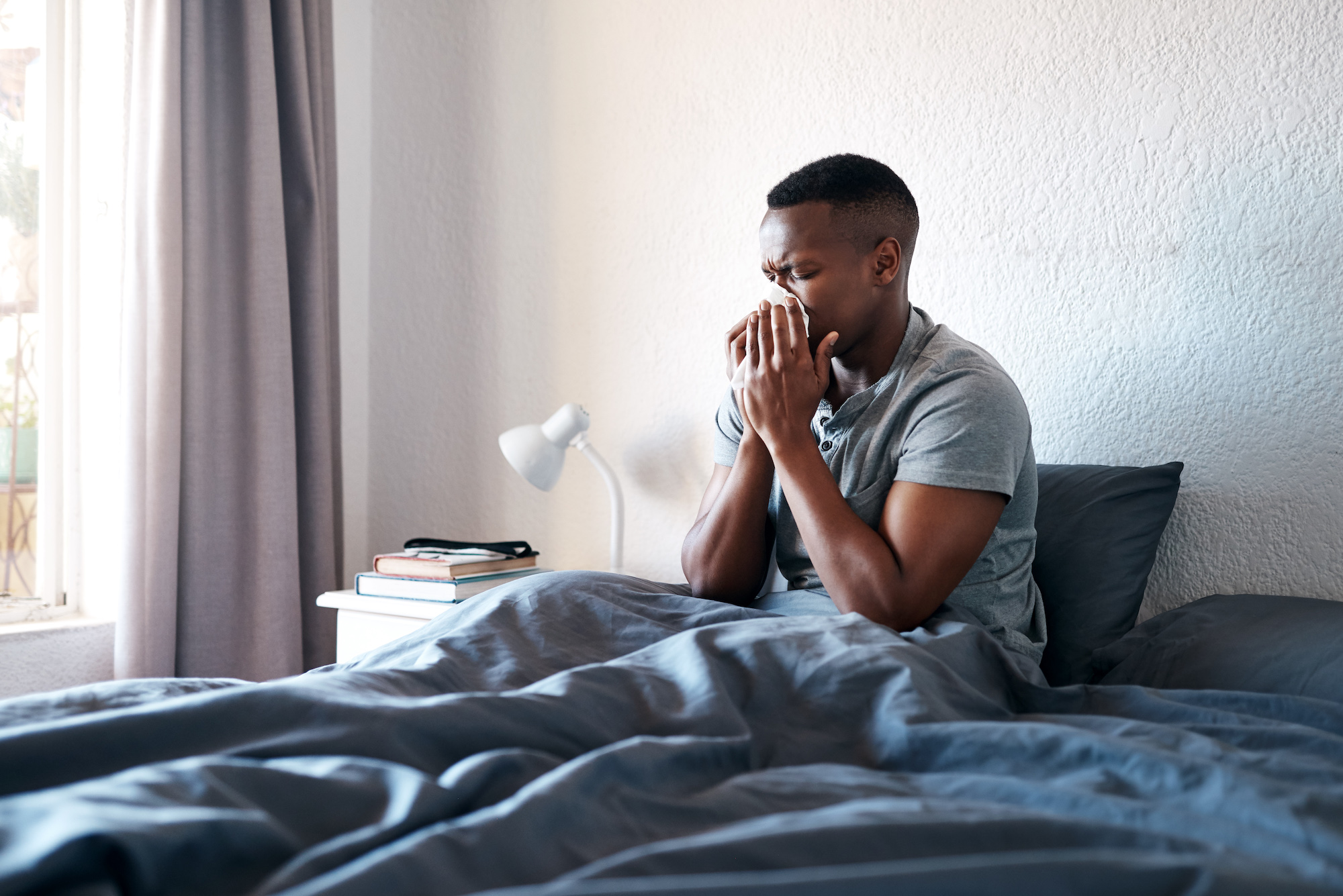 Sick student using a tissue in bed