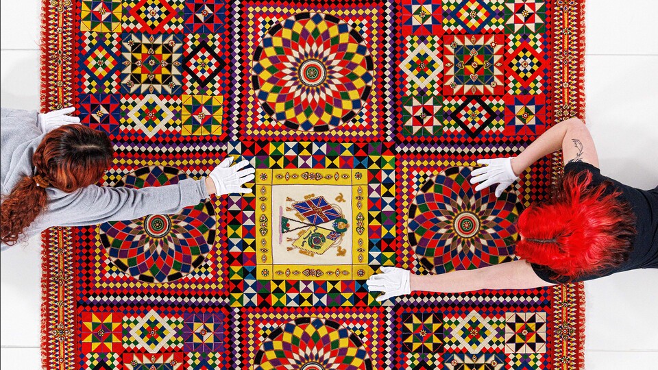 Student workers Olivia Fiore, right, and Inas Hskan, smooth a quilt on a large table so it can be photographed. The quilt is titled “Soldier’s Quilt” c. 1850-1910 and probably made in India. The museum has a dedicated photo room with a camera suspended ab