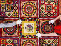Student workers Olivia Fiore, right, and Inas Hskan, smooth a quilt on a large table so it can be photographed. The quilt is titled “Soldier’s Quilt” c. 1850-1910 and probably made in India. The museum has a dedicated photo room with a camera suspended ab