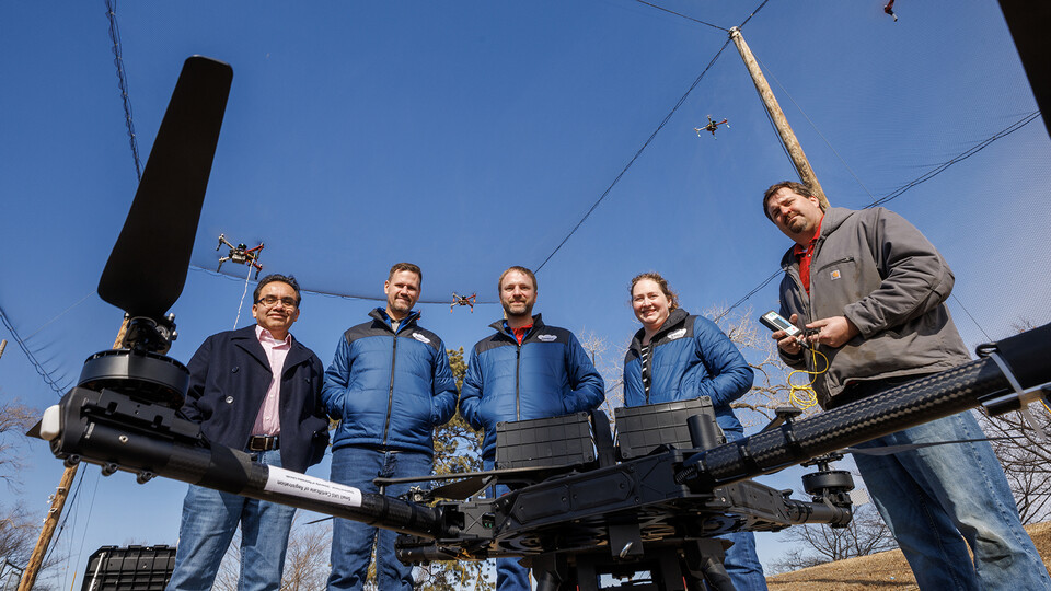 (From left) Francisco Muñoz-Arriola, Justin Bradley, Carrick Detweiler, Brittany Duncan and Trenton Franz pose among unmanned aerial vehicles at the NIMBUS outdoor flying area on Nebraska Innovation Campus. Craig Chandler | University Communications 