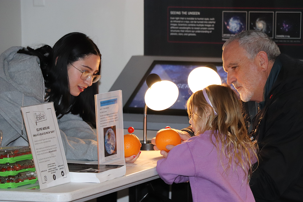 Participants simulated a solar eclipse on Earth using an orange “Sunday with a Scientist” at the University of Nebraska State Museum on March 26. Mike Bergland-Riese | UNL CSMCE