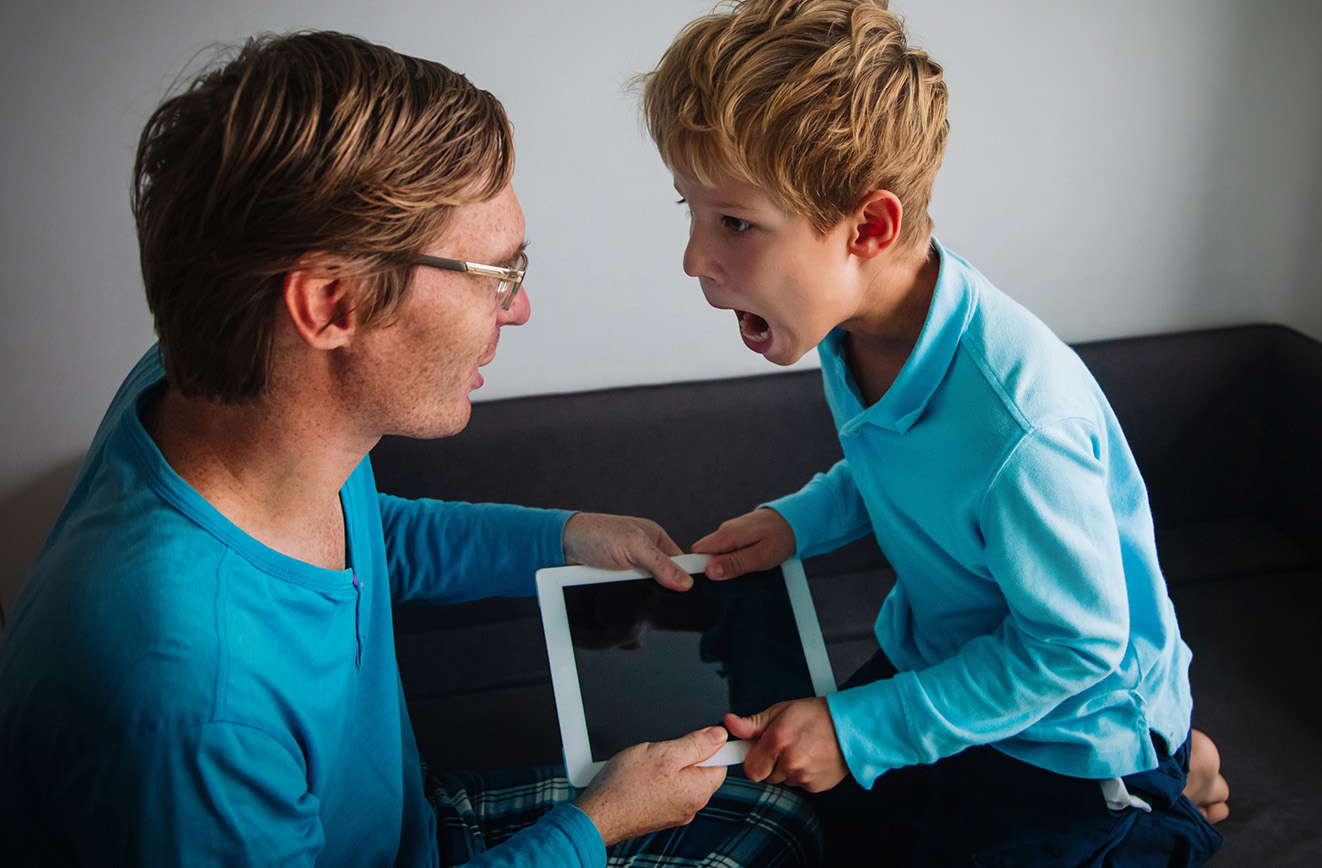 boy yelling at an adult male while grabbing a digital tablet