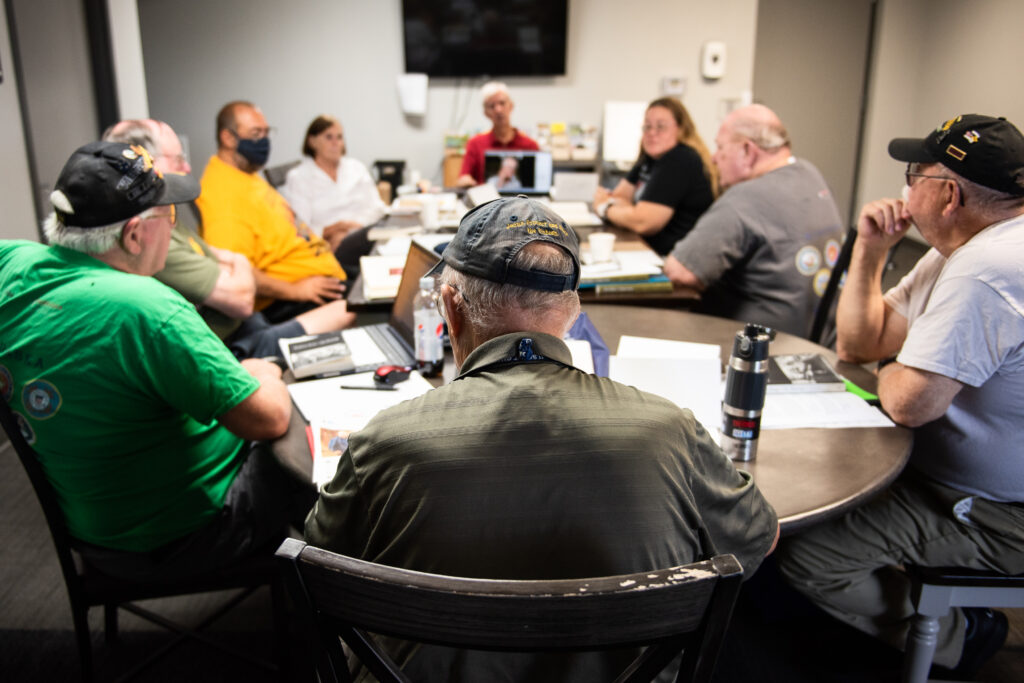 Veterans gather around a table to discuss writing