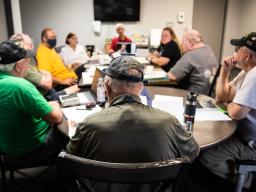 Veterans gather around a table to discuss writing