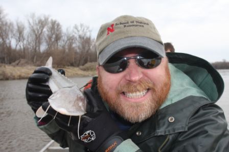 Mark Pegg poses with an endangered pallid sturgeon collected on the Missouri River during a project to send them to a hatchery for spawning and release them back into the wild.