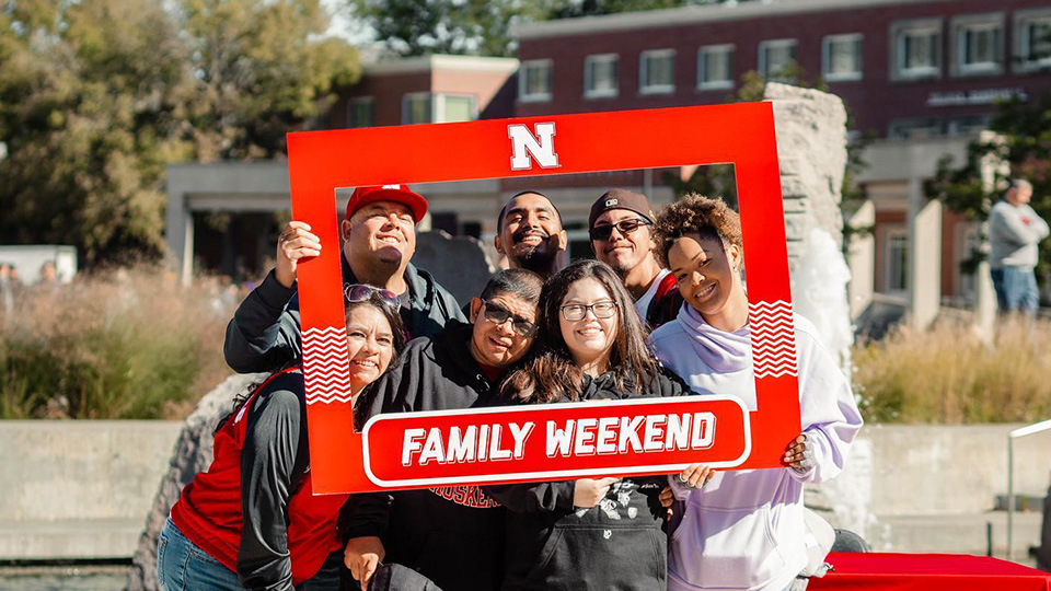 Family Weekend participants pose with a photo frame in front of the Broyhill Fountain