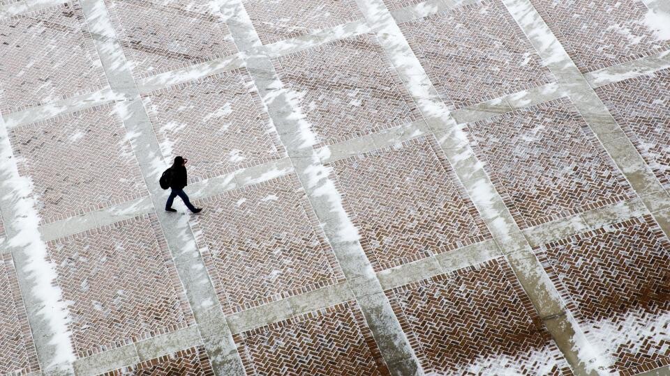 A student walks across the brick plaza outside of East Memorial Stadium. [Craig Chandler | University Communication and Marketing]