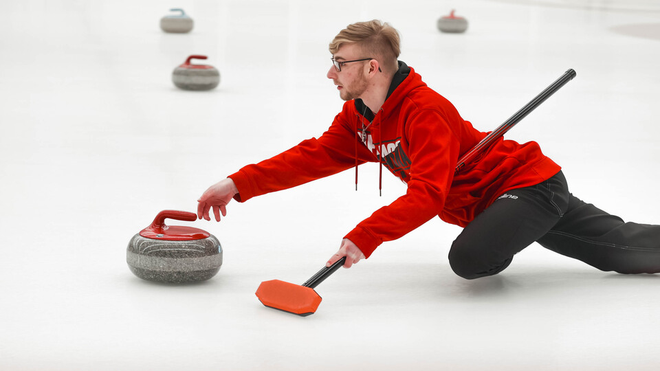 Software engineering major Brett Johnson slides a curling stone Jan. 20 during the club team's bonspiel at the Breslow Ice Hockey Center.