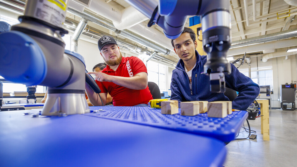 Jacob Hansen and Kunjan Theo Joseph work at making their robotic arm program stack blocks at Nebraska Innovation Studio.  Craig Chandler | UComm
