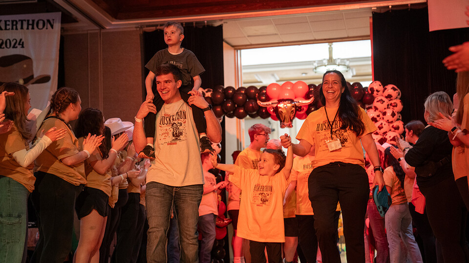 Luke Woosley carries a Miracle Kid on his shoulders as the family enters at HuskerThon. [Kirk Rangel | University Communication and Marketing]