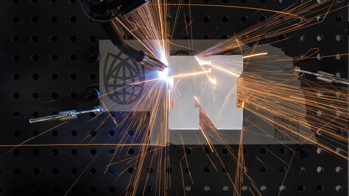 NIS logo with Nebraska logo being welded on the state of Nebraska shape. 