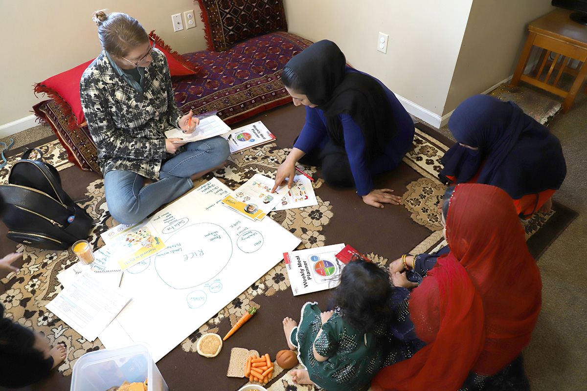 Extension Educator Emily Gratopp joins Cultural Liaison Fariha and an Afghan family to discuss healthy eating. Photo by Marusa Jonas, Nutrition Education Program