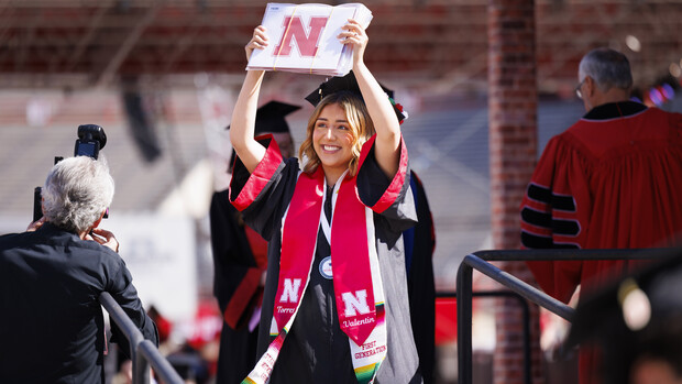 Monzeratt Valentin of Omaha shows off her diplomas to family and friends during the undergraduate commencement ceremony May 18 at Memorial Stadium.