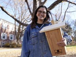 sabella Villanueva, a senior UNL fisheries and wildlife major, stands with a flying squirrel nesting box near Hardin Hall on East Campus.