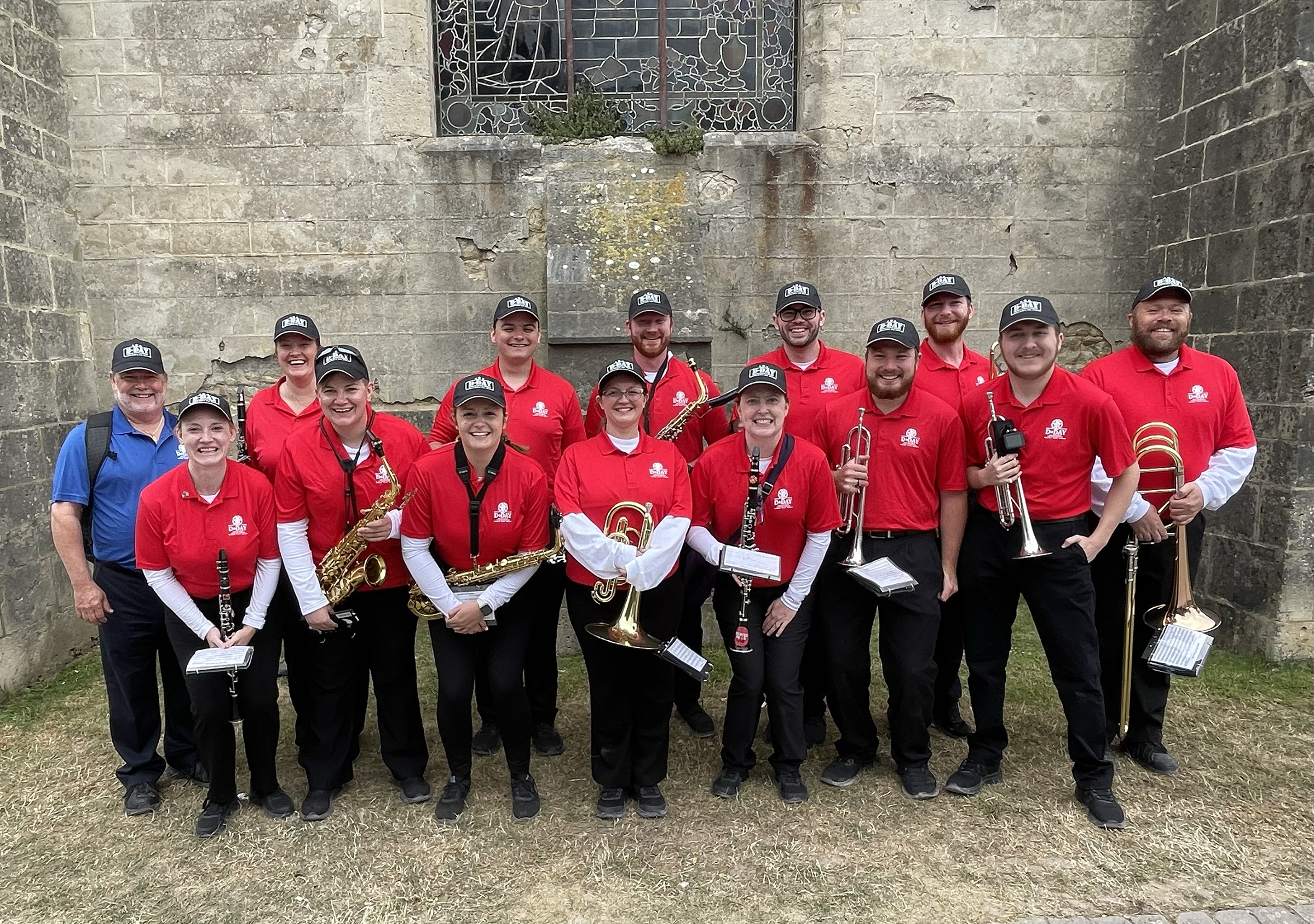 Tony Falcone (left, in blue shirt) with the 13 current and former members of the Cornhusker Marching Band who performed as part of the 80th anniversary D-Day ceremonies in France this summer. Courtesy photo.