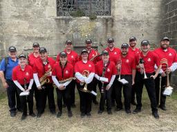 Tony Falcone (left, in blue shirt) with the 13 current and former members of the Cornhusker Marching Band who performed as part of the 80th anniversary D-Day ceremonies in France this summer. Courtesy photo.