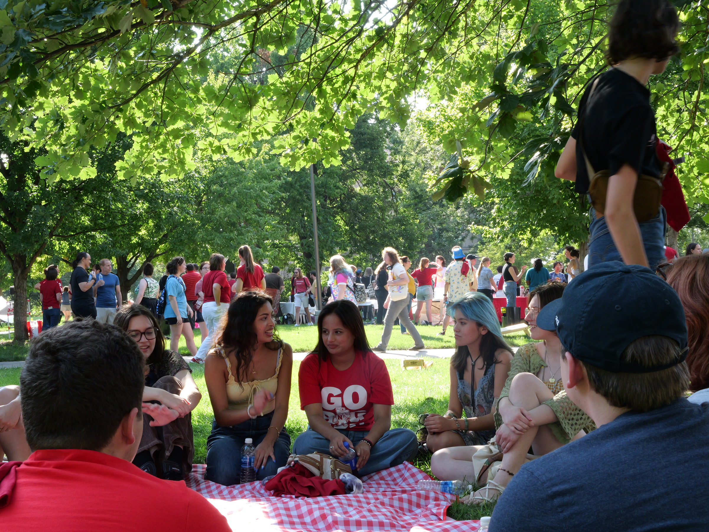 Sanskriti Duwaldi (center, in red shirt), a freshman acting major from Nepal and a member of the first cohort of the Global Arts Academy, visits with students at the Student Welcome Back Picnic on Aug. 22. Photo by Muskan Yadav.