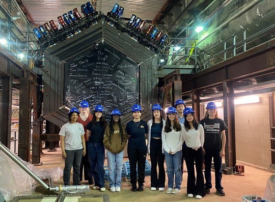 RENEW Pathway Summer School students from the Fermilab and Brookhaven National Laboratories Summer School Exchange Program in 2023 stand in front of the detector of the MINERvA experiment at Fermilab.