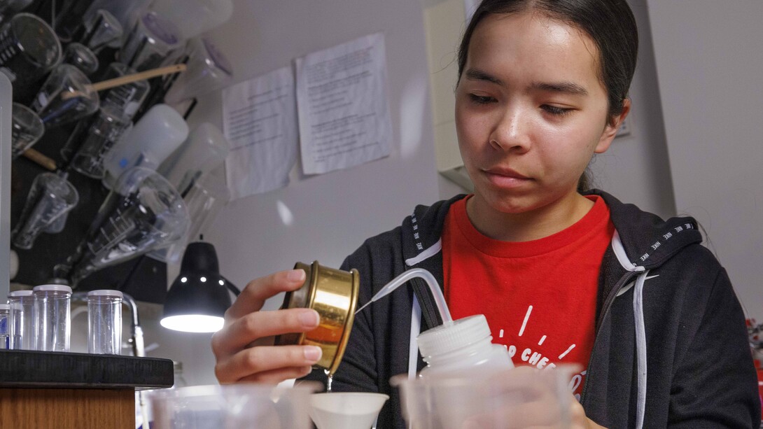 Jasmine Pham, a sophomore mathematics major and UCARE student, washes a sieved soil sample into a container for analysis. She is working with Paul Hanson, a professor in the School of Natural Resources.