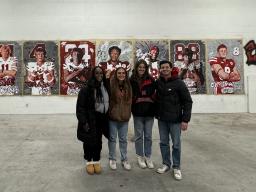 Left to right:  Michelle Reese, Maddie Vanderbur, Lea Bushey and Micah Fullinfaw stand in front of the mural they created to spotlight the players signed on National Signing Day by the Nebraska Football team. Courtesy photo.