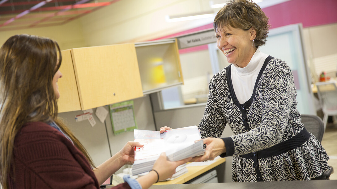 Teri Kaluza smiles as she hands a project off to a customer in the Pixel Lab. Kaluza is among the women who have been featured by the Chancellor's Commission on the Status of Women. 