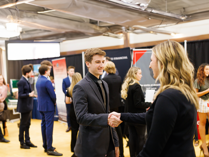 A student meets an employer at a previous University Career + Internship Fair.