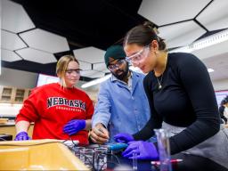 Three students working on a chemistry experiment.