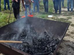Kim Slezak, a certified forester with the Nebraska Forest Service, leads the biochar demonstration with an Oregon Kiln and rakes the biochar after adding water to stop the burning/pyrolyzing at the biochar field day Sept. 22.