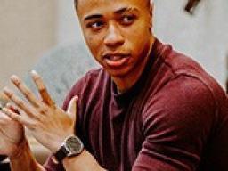 Three people sitting at a table in front of computer talking