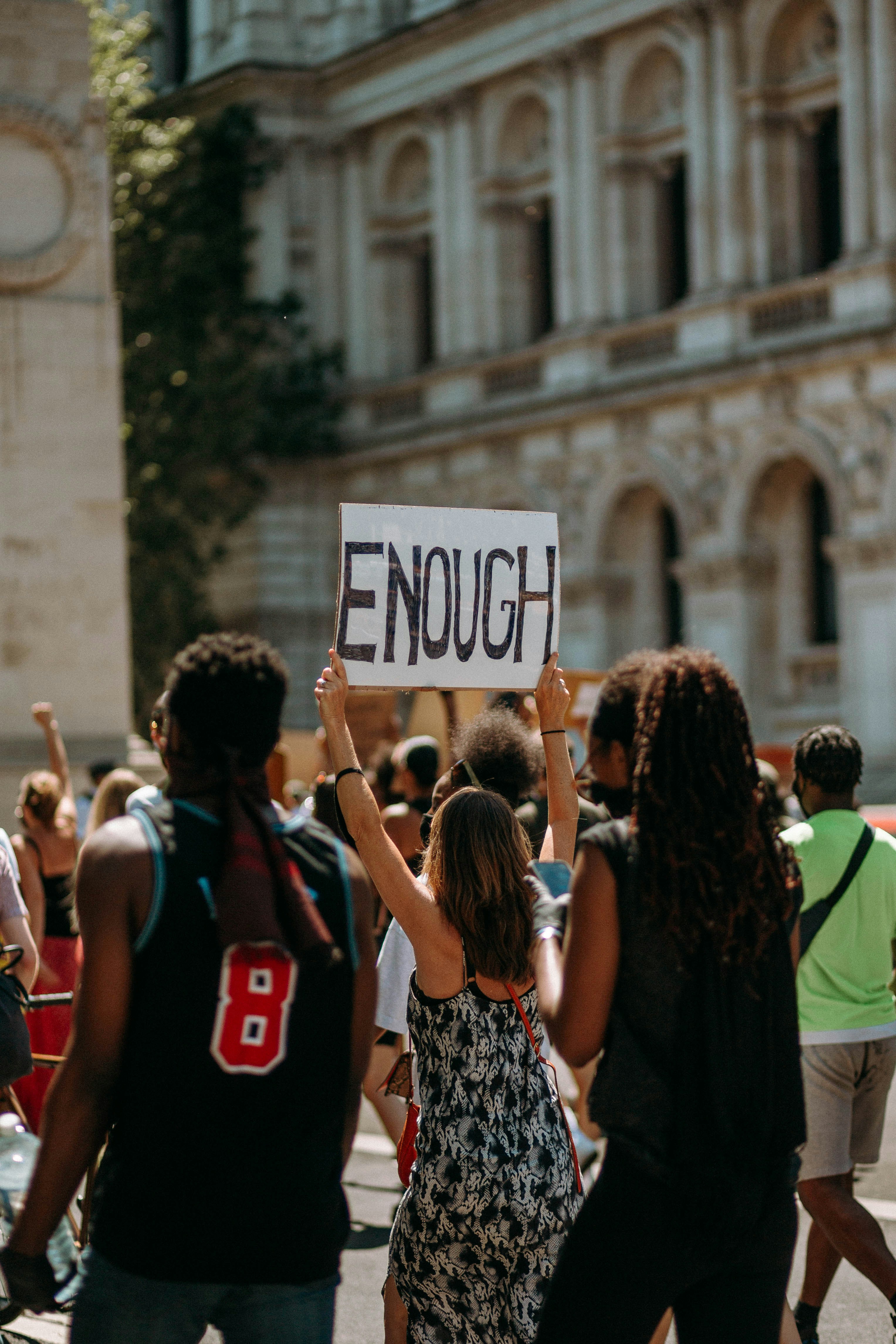 Image of students protesting with a sign reading "ENOUGH"
