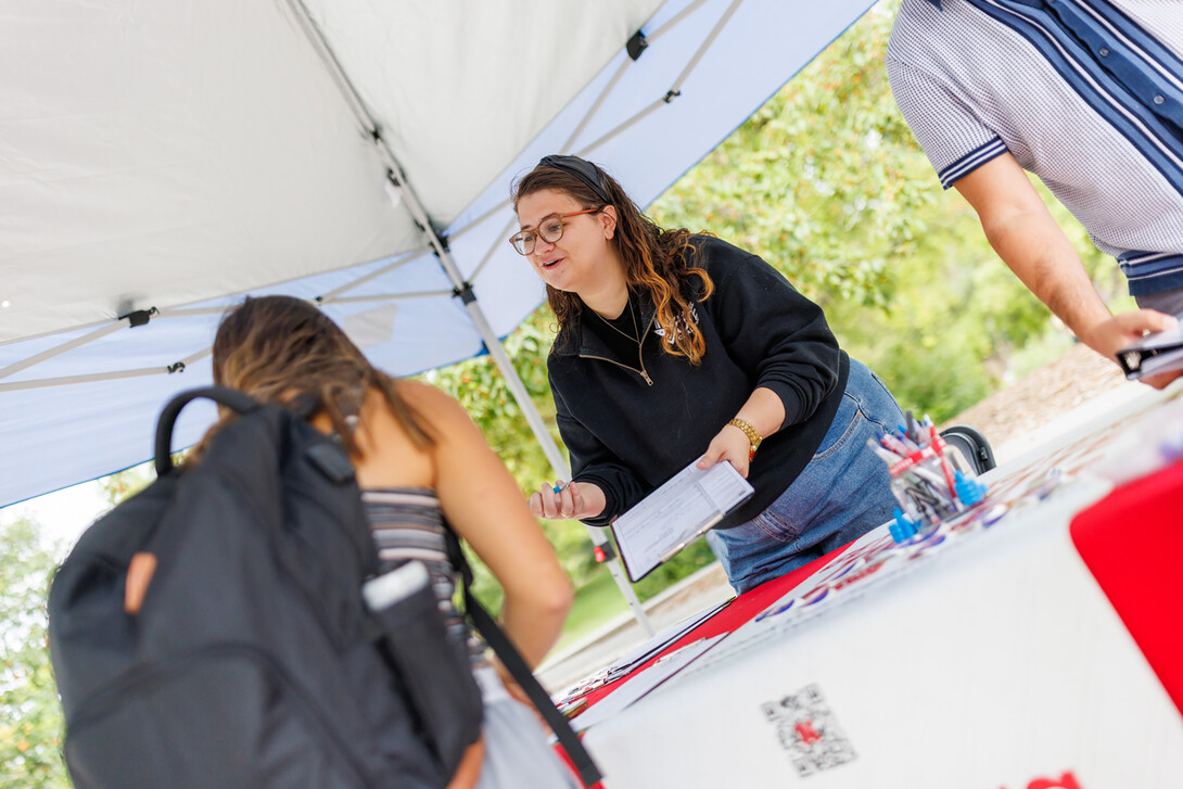 Maggie Nielsen with the Husker Vote Coalition provides voter registration information to a student.