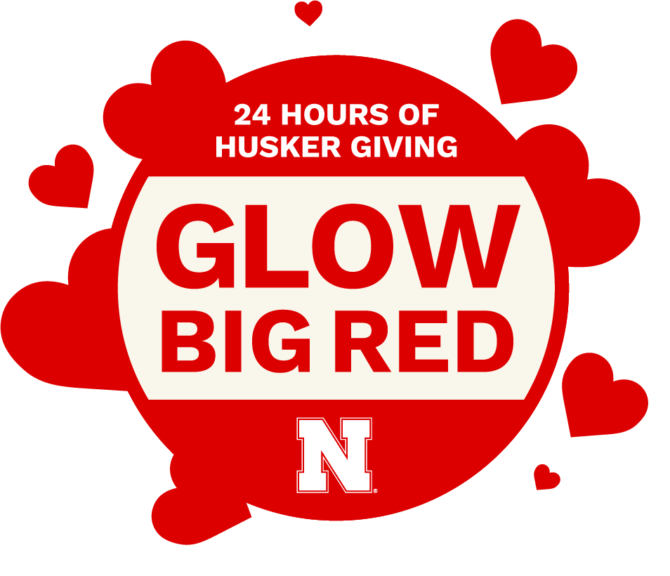 A cream background with scarlet hearts around a scarlet circle. Inside the circle it reads "24 Hours of Husker Giving: Glow Big Red"
