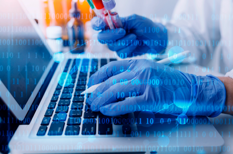 Medical gloved hands holding a vile in their right hand and coding with their left hand.