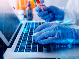 Medical gloved hands holding a vile in their right hand and coding with their left hand.