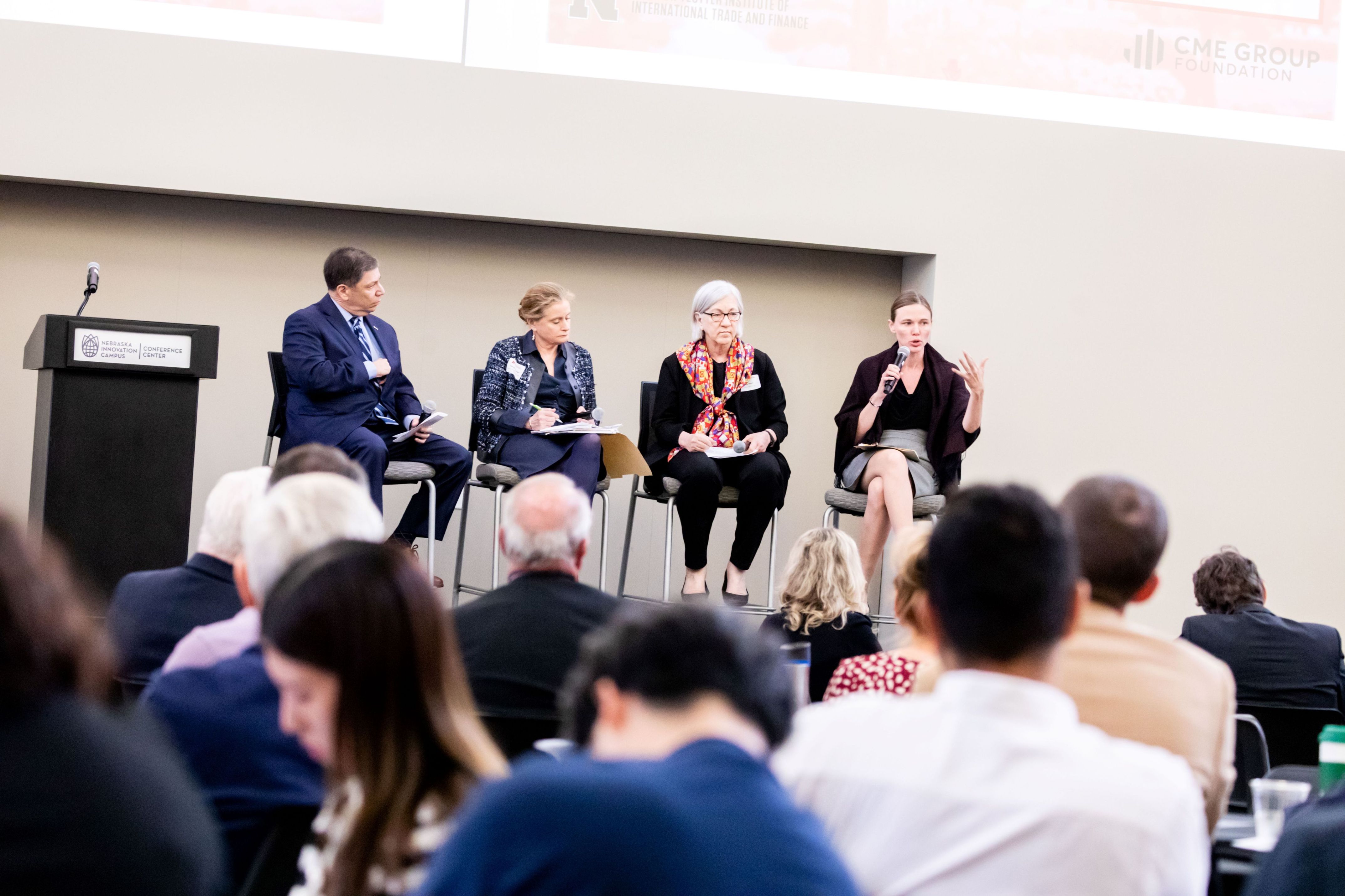 Kathleen Claussen, on a panel with Ken Levinson, Meredith Broadbent, and Amy Proges, speaking towards the audience.