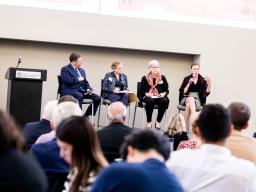 Kathleen Claussen, on a panel with Ken Levinson, Meredith Broadbent, and Amy Proges, speaking towards the audience.