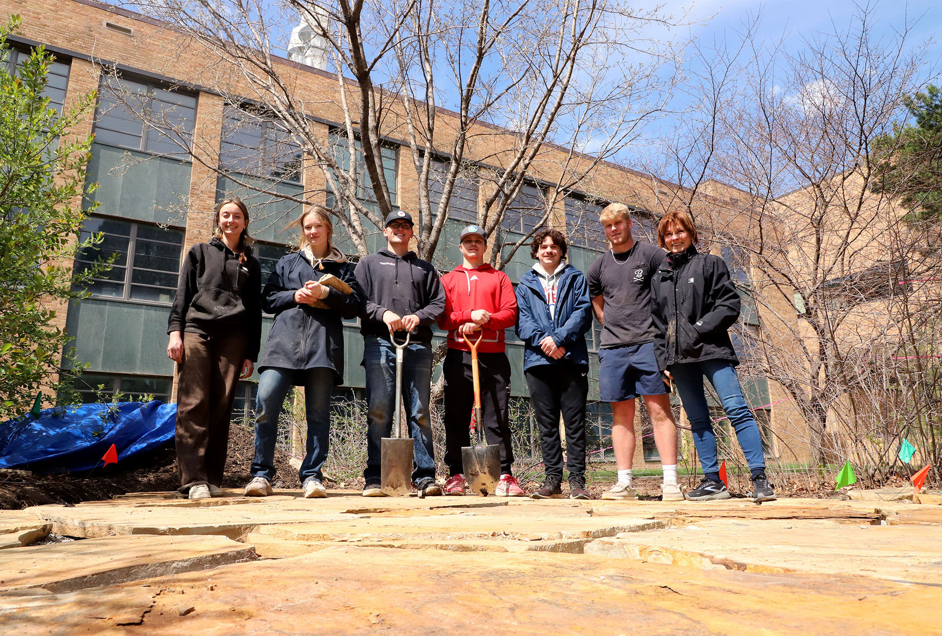 Students in Plant and Landscape Systems 300 Introduction to Construction Management class, taught by Kim Todd (right), build a flagstone patio behind Keim Hall near the Backyard Farmer garden on East Campus. 