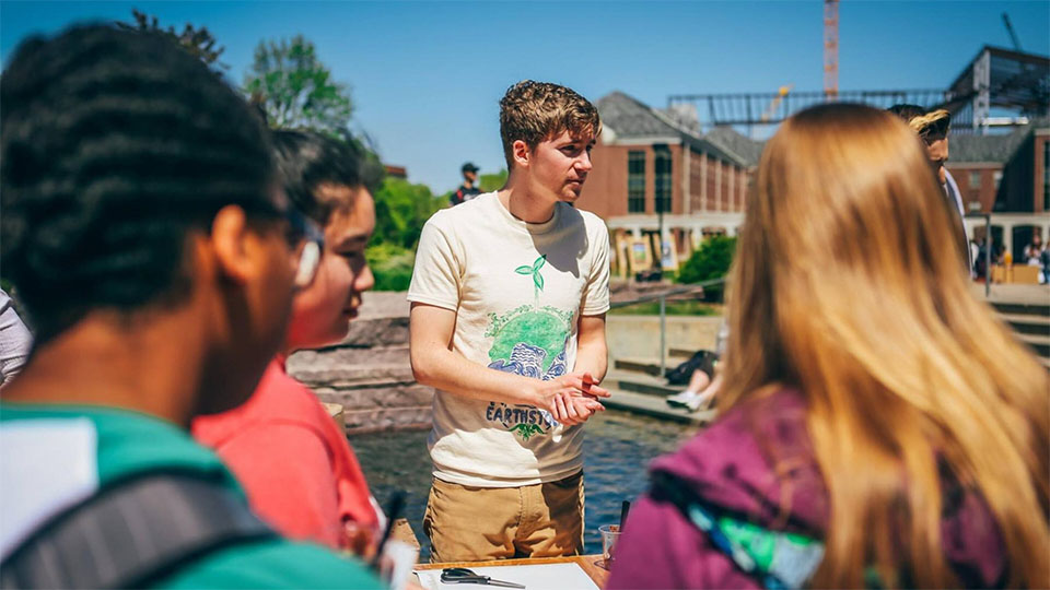 A group of students speak with an Earthstock vendor on the Nebraska Union's Memorial Plaza.